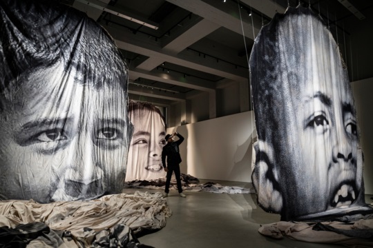 The-artist-JR-portrayed-in-one-of-the-rooms-where-three-original-tarps-are-on-display-Ph.-Andrea-Guermani